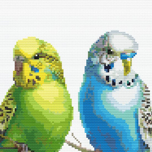 Close-up of Colorful Budgies Cross Stitch Pattern showing yellow and blue budgies, feather detail, and visible counted cross stitch texture.