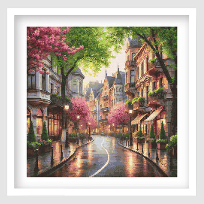 Framed artwork of a picturesque street scene with cherry blossoms and buildings.