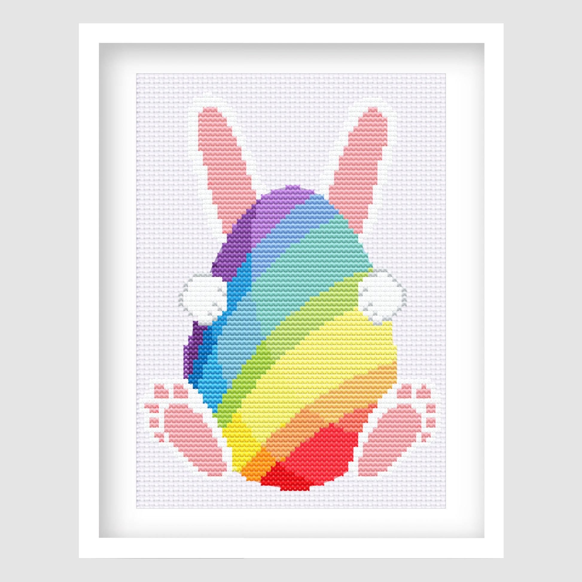 Rainbow bunny cross stitch pattern shown framed in white.