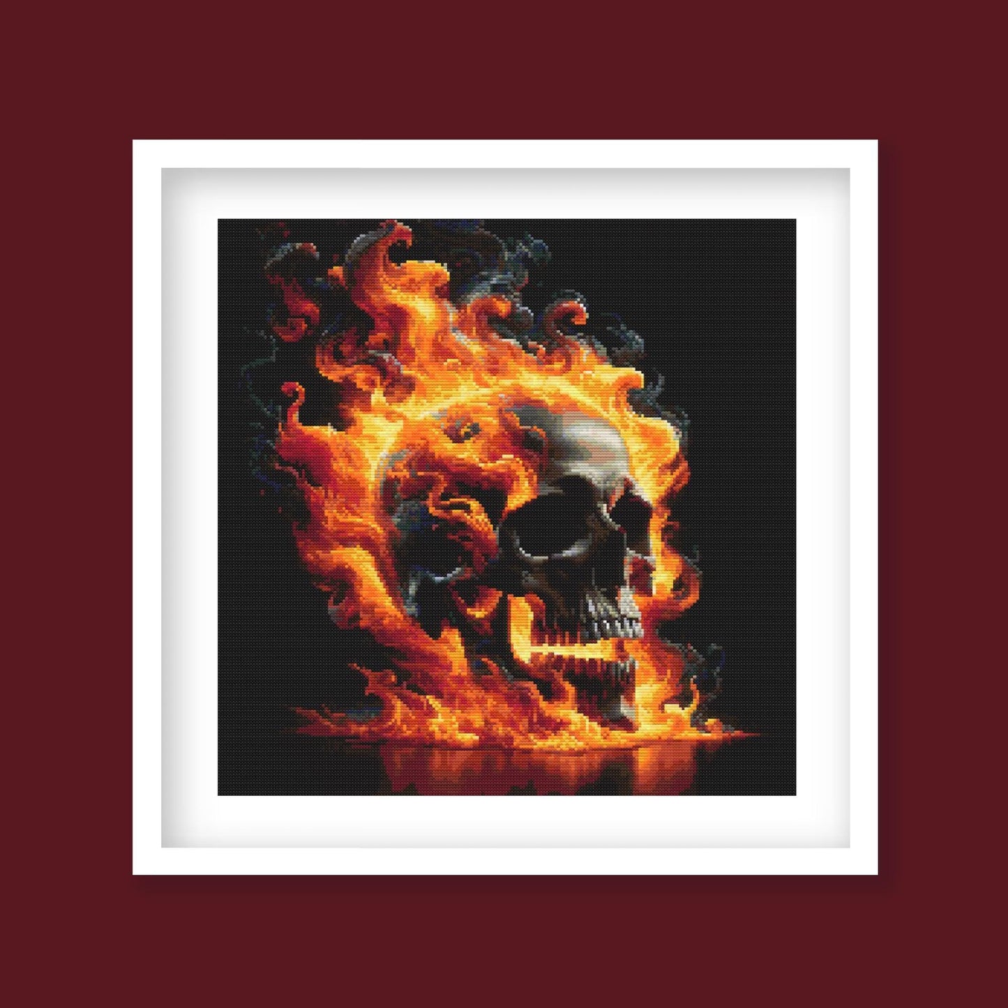 Flaming Skull Cross Stitch Pattern displayed in a dark red frame, showing the completed design as dramatic gothic cross stitch wall decor.