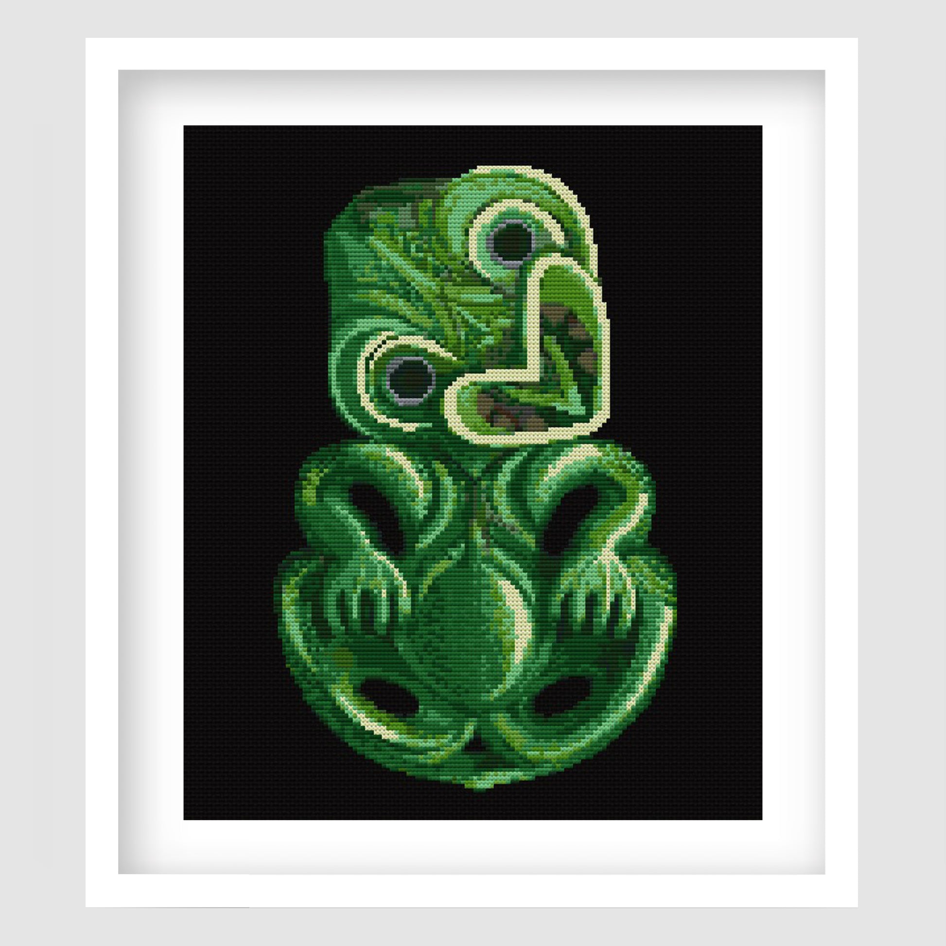 Green tiki cross stitch pattern featuring a carved pounamu-style Māori-inspired figure on a black background, with detailed green shading and bold cultural design.
