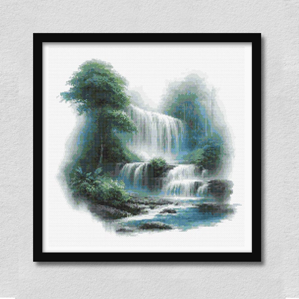 Waterfall cross stitch pattern displayed in a black frame, featuring lush green rainforest scenery, cascading waterfalls, misty mountains, and a blue flowing stream.
