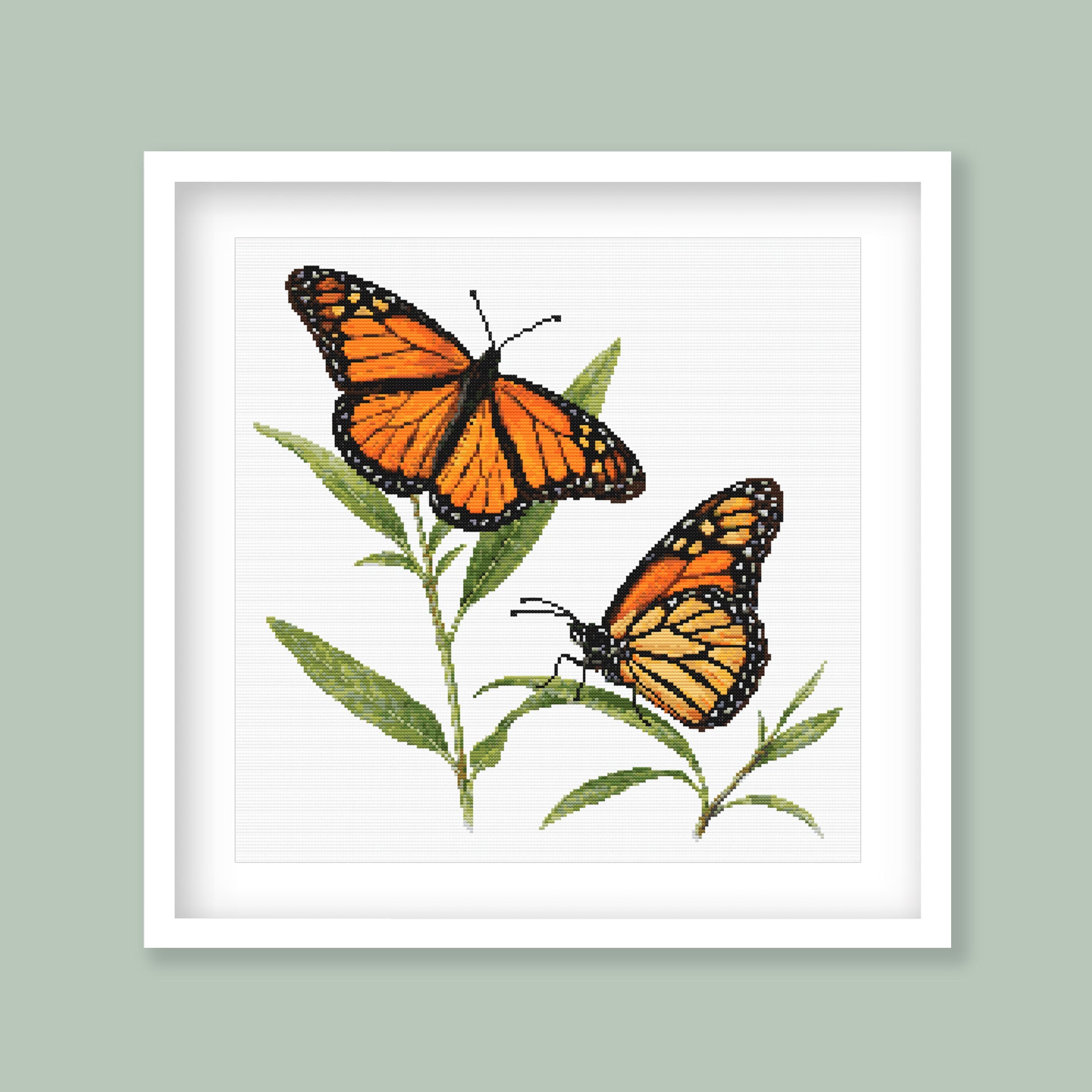 Monarch Butterfly Cross Stitch Pattern displayed in a sage green frame, styled as botanical wall art.