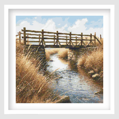 Wooden bridge over a stream with tall grasses and a blue sky.