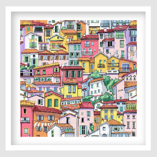 Colourful village cross stitch pattern featuring a dense hillside scene of bright pastel houses, tiled rooftops, balconies and detailed architectural windows.