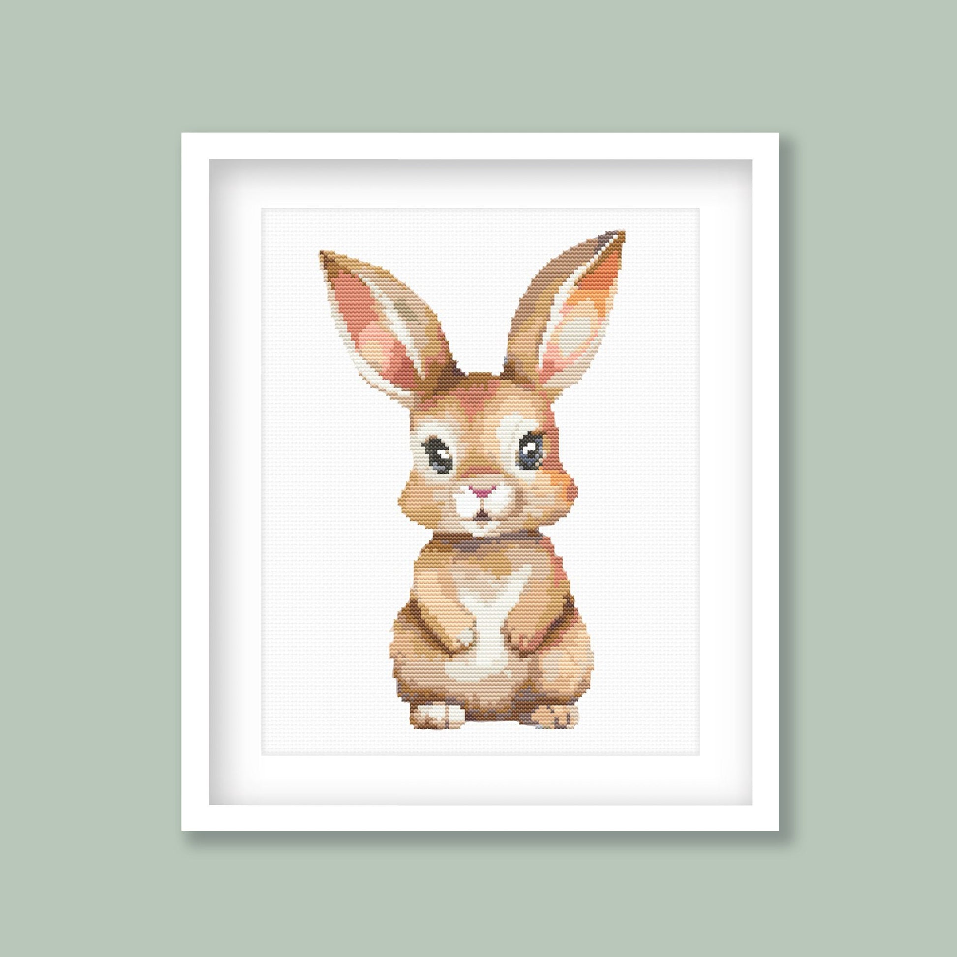 Baby Rabbit Cross Stitch Pattern displayed as framed wall art with a soft bunny design on a sage green background for nursery or kids room decor.