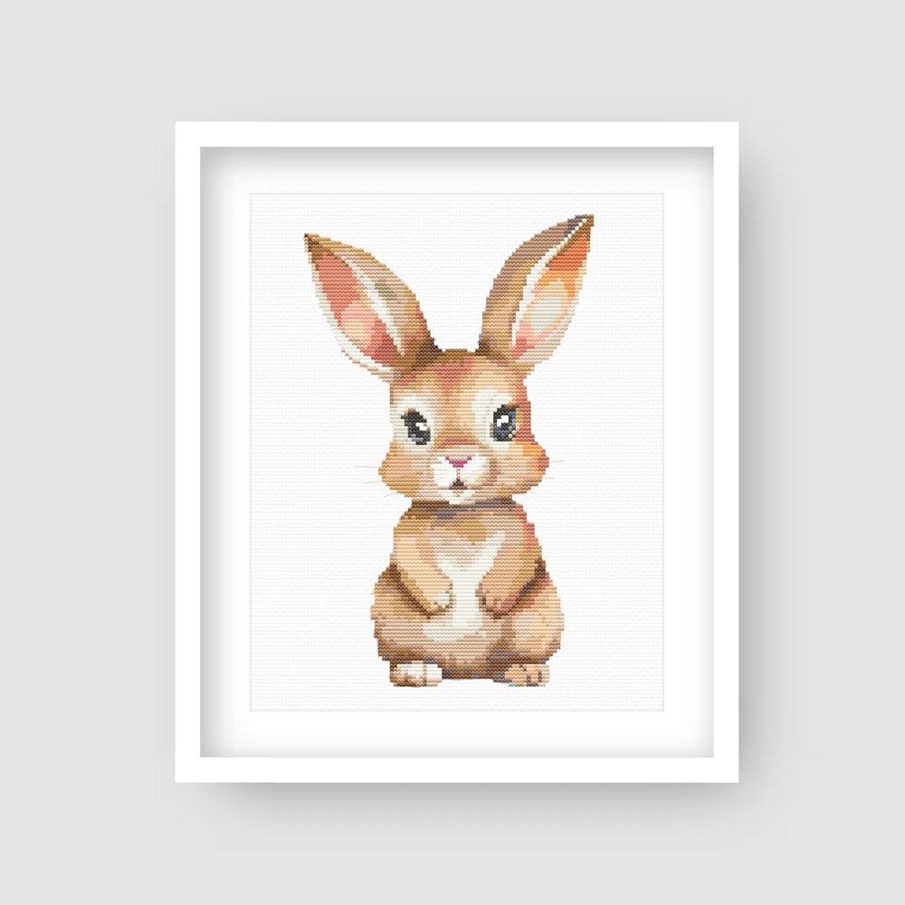 Baby Rabbit Cross Stitch Pattern displayed in a white frame with a soft bunny design for nursery wall art or baby room decor.