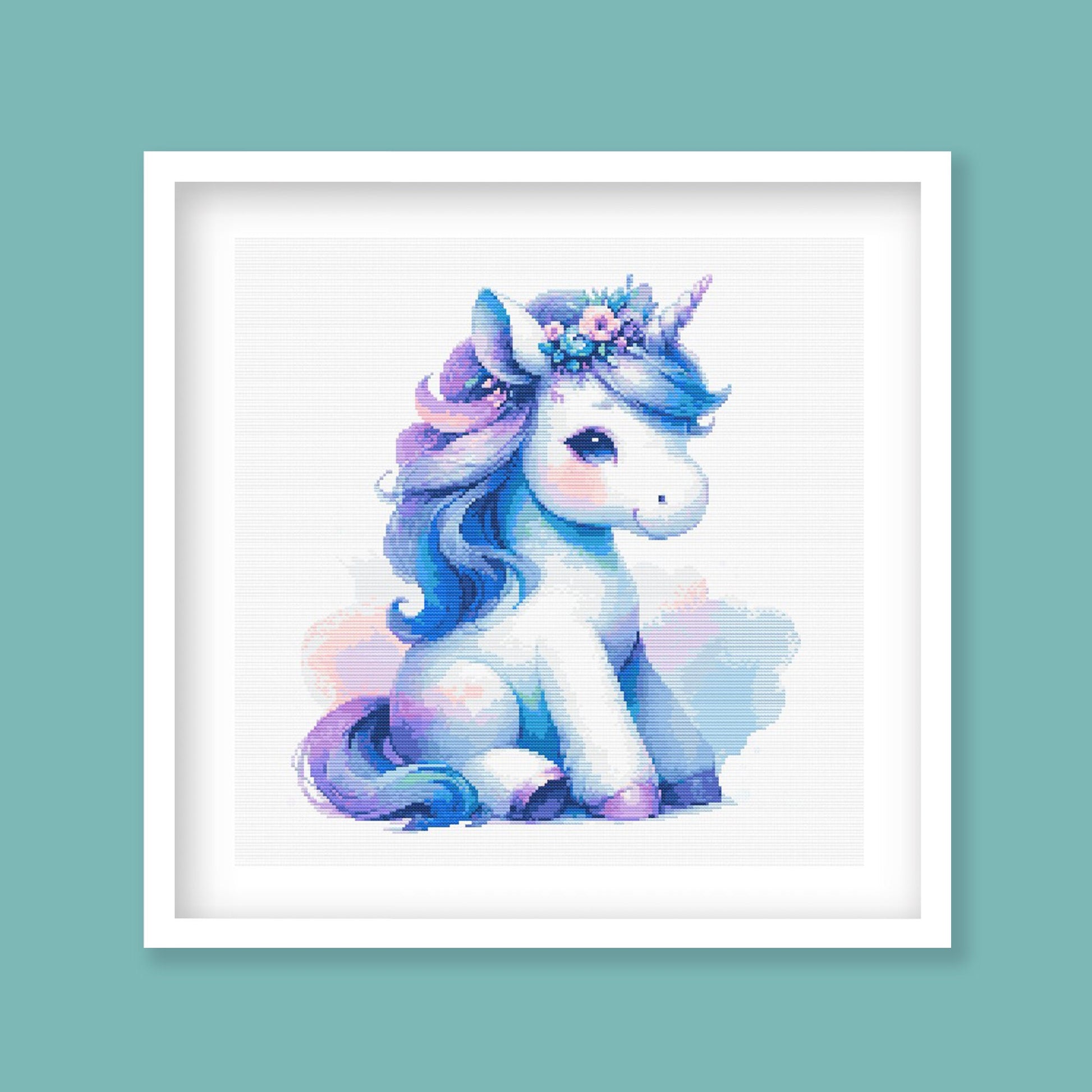 Baby Unicorn Cross Stitch Pattern displayed in a blue frame with a pastel unicorn design for nursery wall art or children’s room decor.