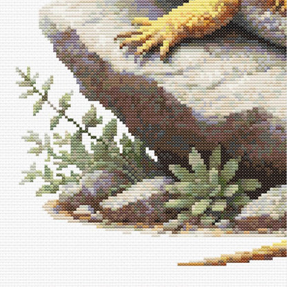 Close up of a Cross stitched lizard on a rock with plants