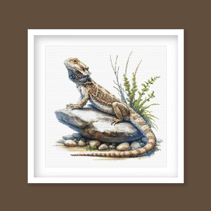 Bearded Dragon Lizard Cross Stitch Pattern displayed as framed wall art with a detailed reptile, textured scales, rocky ground, and natural desert-style detail.
