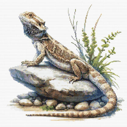 Bearded Dragon Lizard Cross Stitch Pattern featuring a detailed bearded dragon resting on rocks with grass detail and natural reptile styling.