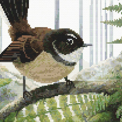 Close-up of the Fantail Pīwakawaka cross stitch pattern showing detailed feathers and native fern foliage.