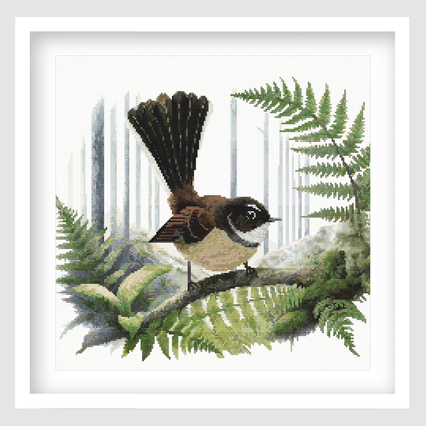 Framed Fantail Pīwakawaka cross stitch featuring a New Zealand fantail perched among native fern fronds.