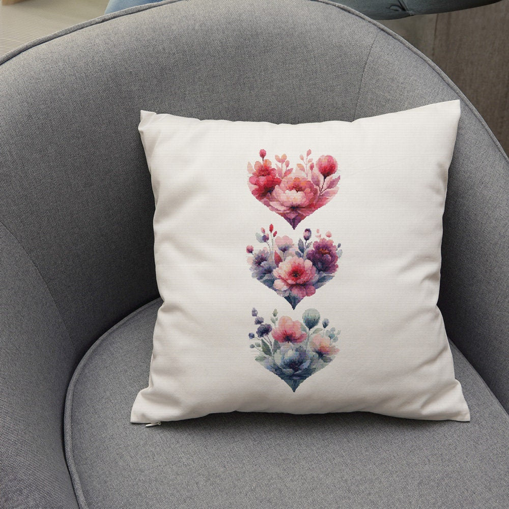 Floral Heart Cross Stitch Pattern Set shown as a cushion preview with pink and blue floral heart designs on a soft home decor background.