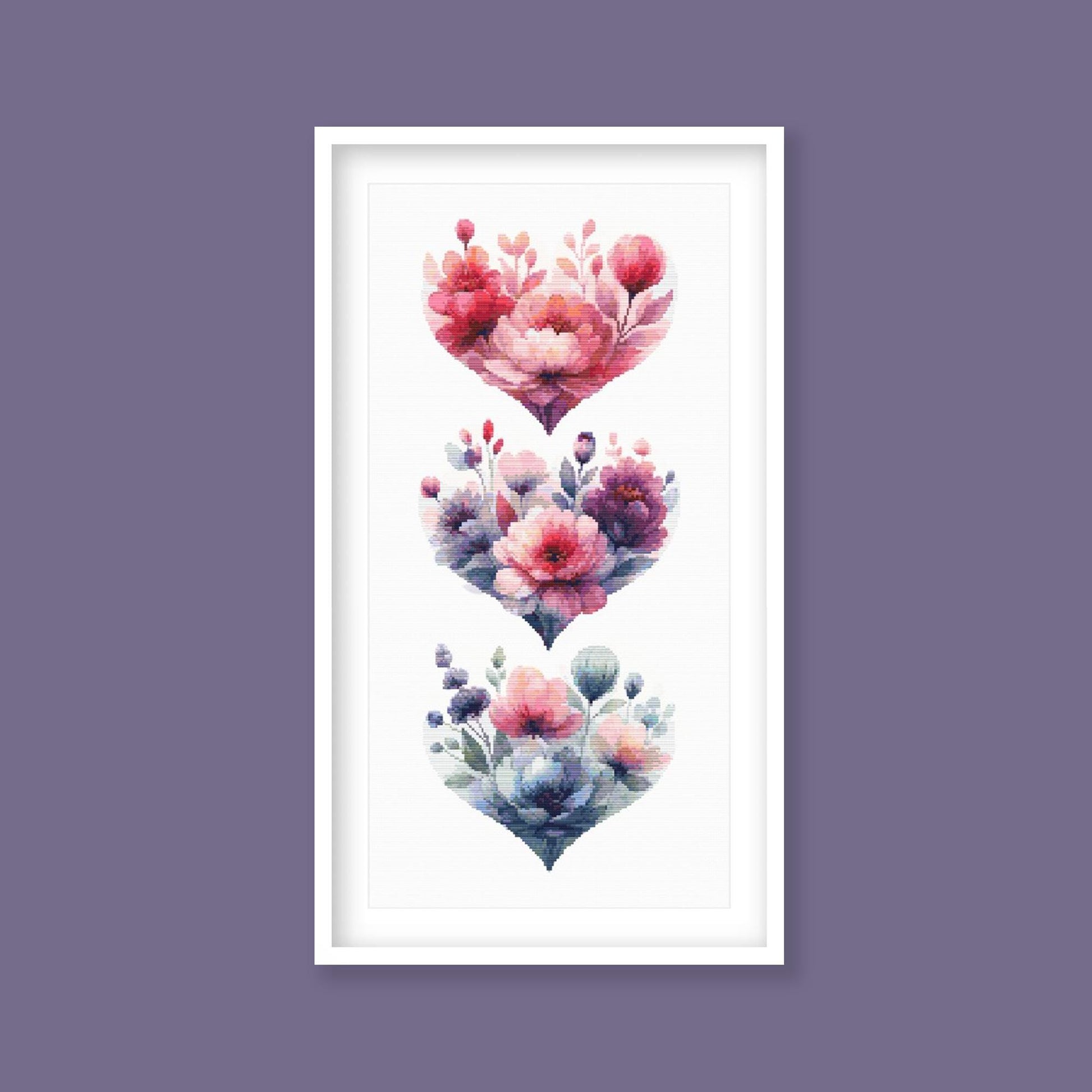 Floral Heart Cross Stitch Pattern Set displayed as framed wall art with stacked heart designs, soft pink flowers, blue leaves, and romantic botanical detail.