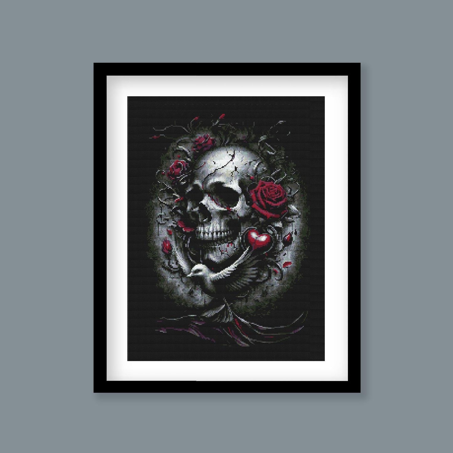 Gothic Skull and Roses Cross Stitch Pattern displayed as framed wall art with a dark skull, red rose detail, and dramatic gothic styling.