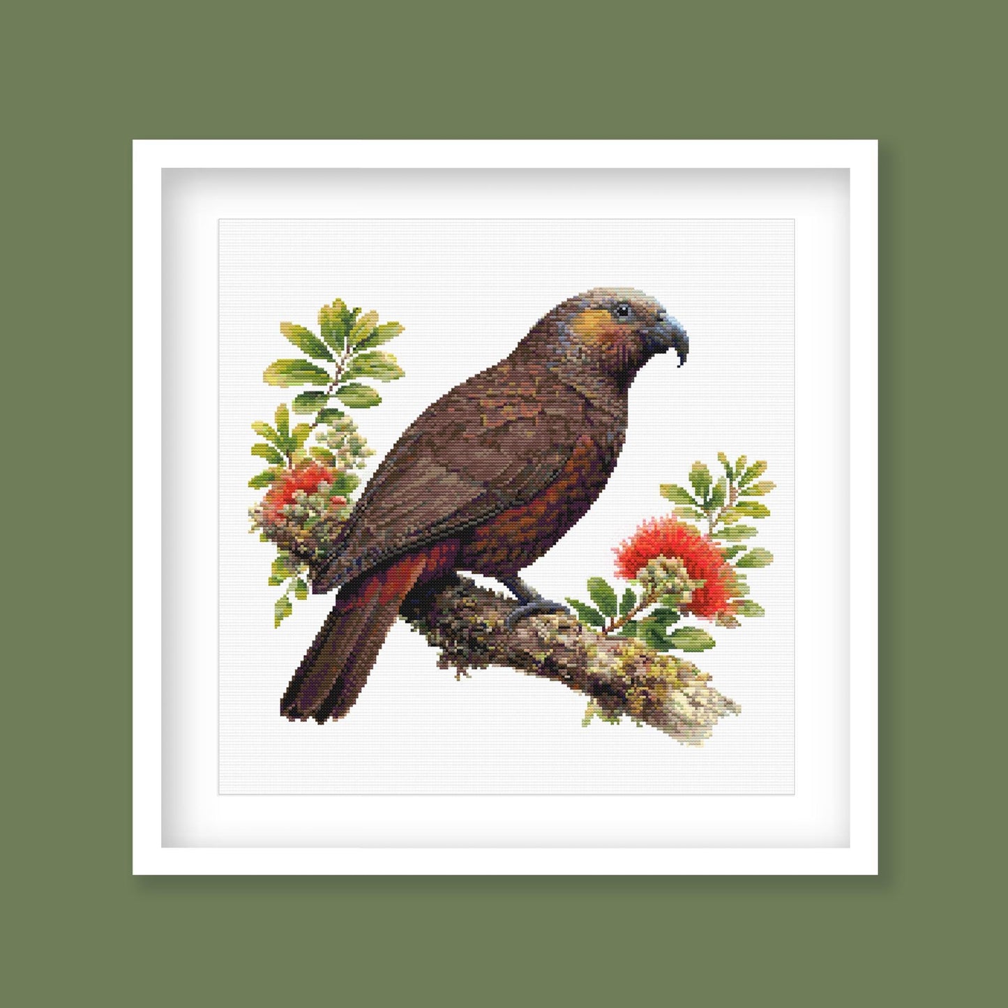 New Zealand Kākā Cross Stitch Pattern displayed in a green frame as native bird wall art with pōhutukawa flowers and natural New Zealand styling.