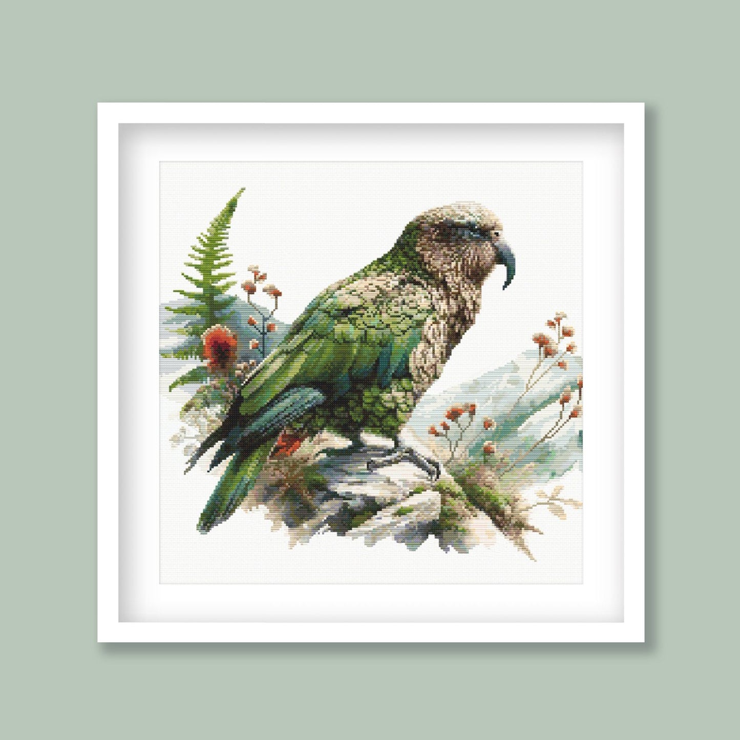 New Zealand Kea Cross Stitch Pattern displayed in a green frame with native alpine parrot artwork and natural New Zealand styling.