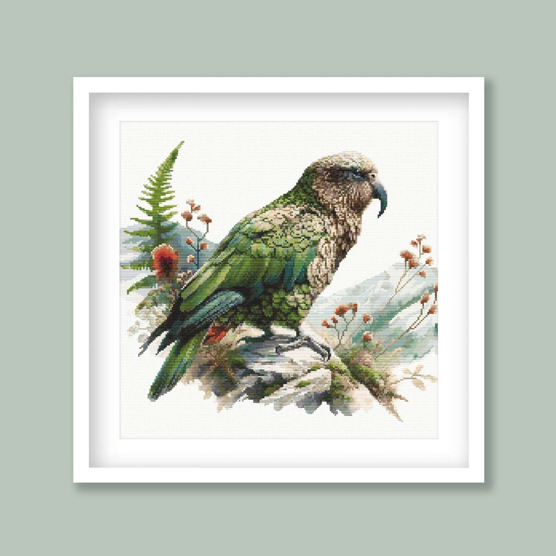 New Zealand Kea Cross Stitch Pattern displayed in a green frame with native alpine parrot artwork and natural New Zealand styling.