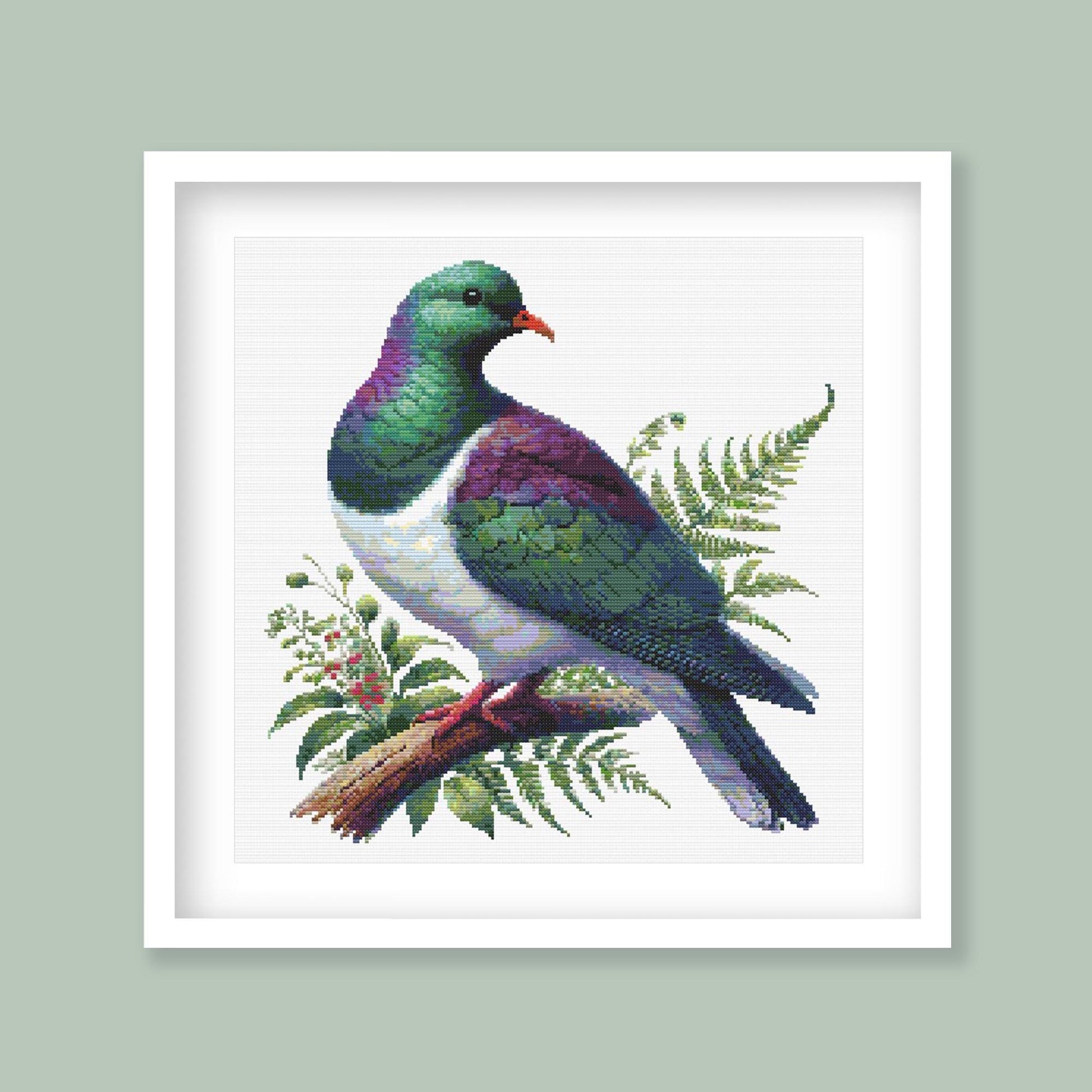 New Zealand Kererū Cross Stitch Pattern displayed in a green frame with native wood pigeon artwork, fern foliage, and natural New Zealand styling.