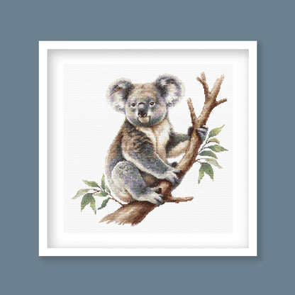 Koala Cross Stitch Pattern displayed in a black frame as Australian wildlife wall art with a koala and eucalyptus branch.