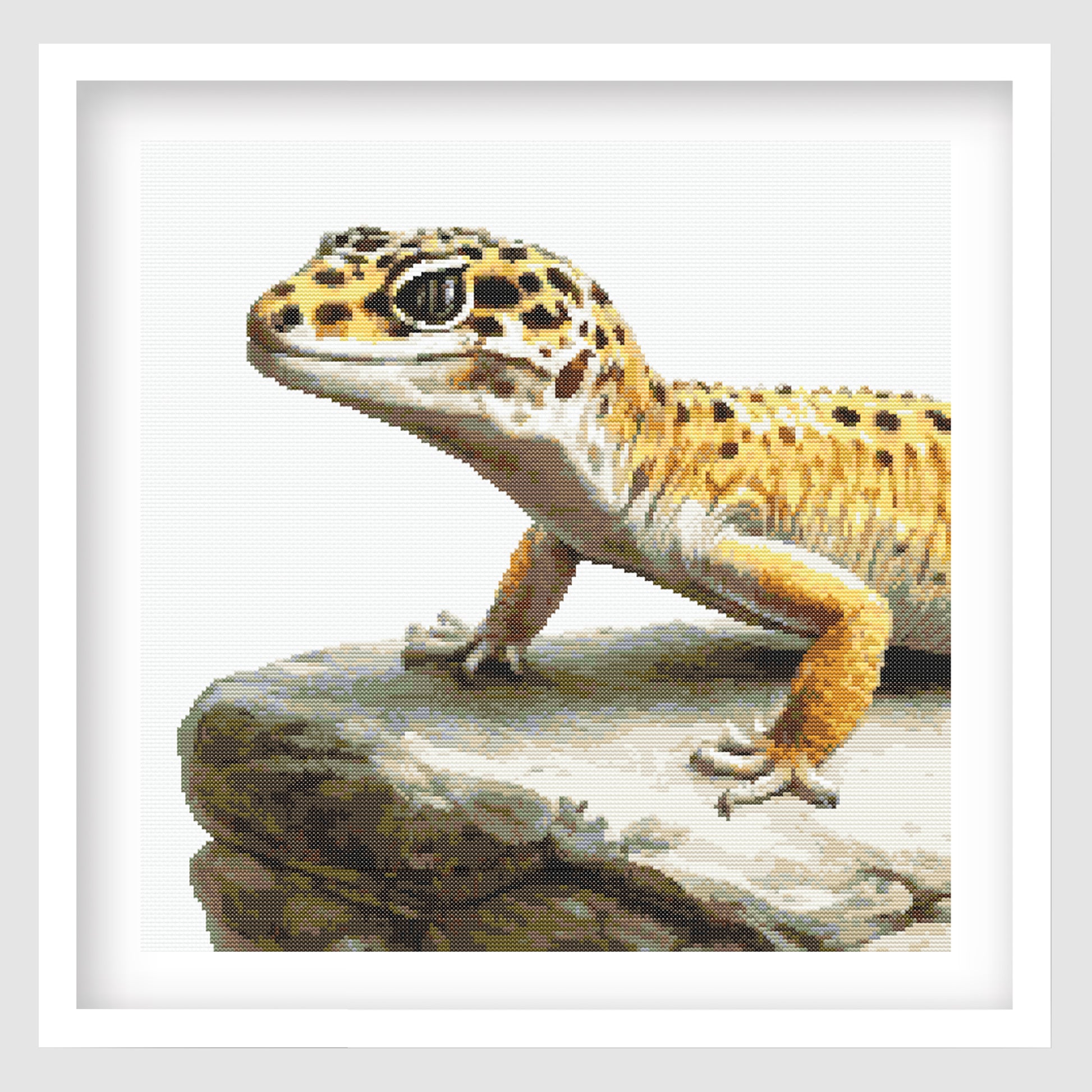 Leopard Gecko Cross Stitch Pattern displayed as framed wall art with a detailed spotted gecko resting on a rock ledge.