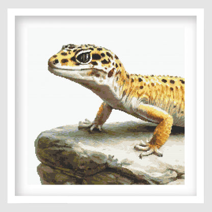 Leopard Gecko Cross Stitch Pattern displayed as framed wall art with a detailed spotted gecko resting on a rock ledge.
