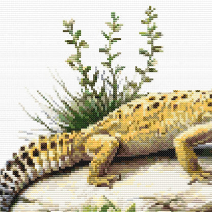 Close-up of Leopard Gecko Cross Stitch Pattern showing the gecko body, striped tail, green plant detail, and textured rock ledge.