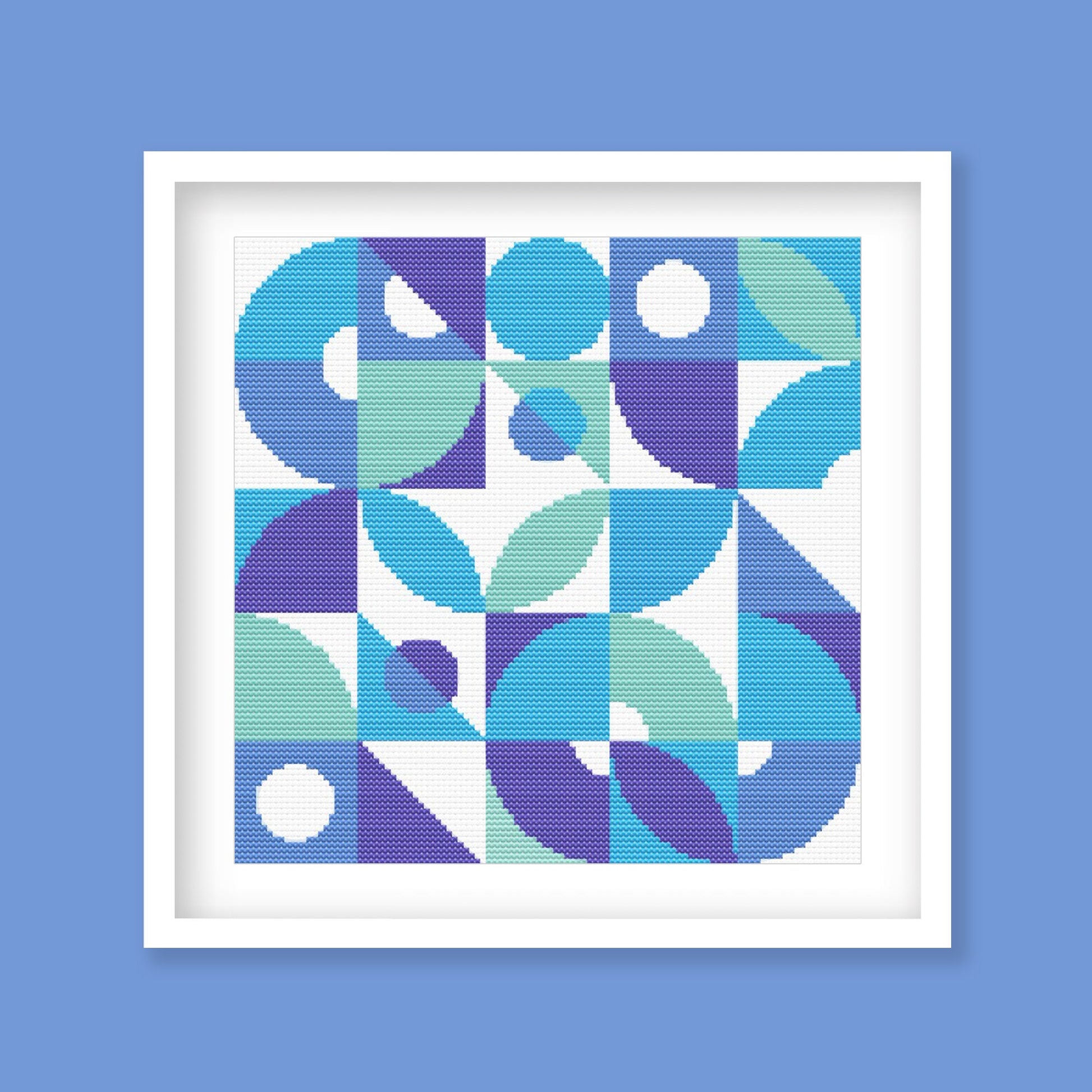 An image of a geometric cross stitch moced up into a frame.