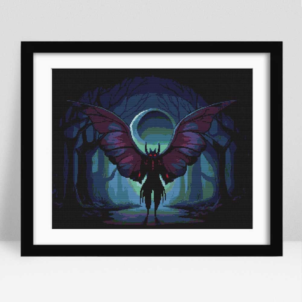 Mothman Cross Stitch Pattern displayed in a black frame as gothic wall art with a winged creature, glowing eyes, and moonlit forest detail.