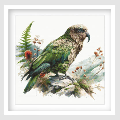 New Zealand Kea Cross Stitch Pattern displayed as framed wall art with a native alpine parrot, green feathers, mountain foliage, and natural New Zealand bird detail.