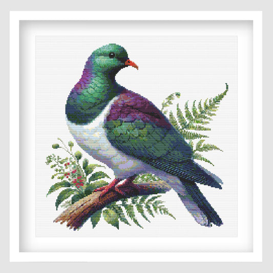 New Zealand Kererū Cross Stitch Pattern displayed as framed wall art with a native wood pigeon, green and purple feathers, fern foliage, and natural bird detail.