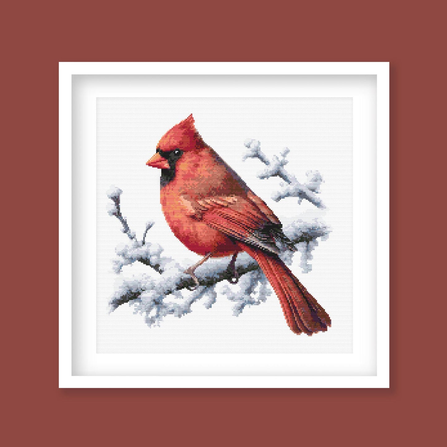 Northern Cardinal Bird Cross Stitch Pattern displayed as framed wall art with a vivid red cardinal perched on snowy branches.