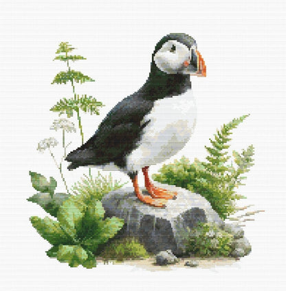 Puffin Cross Stitch Pattern featuring a coastal puffin standing among rocks and greenery with bright beak detail and natural wildlife styling.