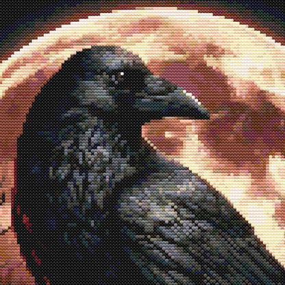 Close-up of a raven cross stitch pattern showing dark feather detail, a glowing blood moon background and dramatic gothic stitching.