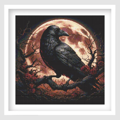 Raven under a blood moon cross stitch pattern displayed in a black frame, featuring gothic dark fantasy artwork with a raven, skulls, roses, branches and a glowing moon.