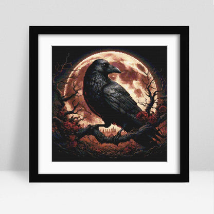 Raven Under a Blood Moon cross stitch pattern displayed as framed wall art in a modern room setting, ideal for gothic decor and handmade gifts.