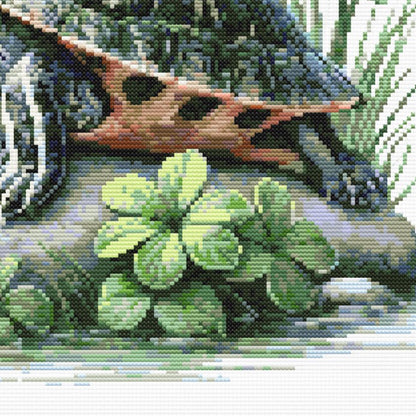 Close-up of Red-Eared Slider Turtle Cross Stitch Pattern showing shell markings, turtle legs, green plant detail, and visible counted cross stitch texture.