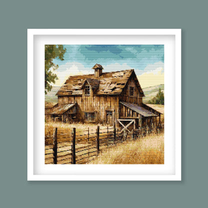 Rustic Barn Cross Stitch Pattern displayed as framed wall art with an old wooden barn, rural fencing, golden grass, and countryside detail.