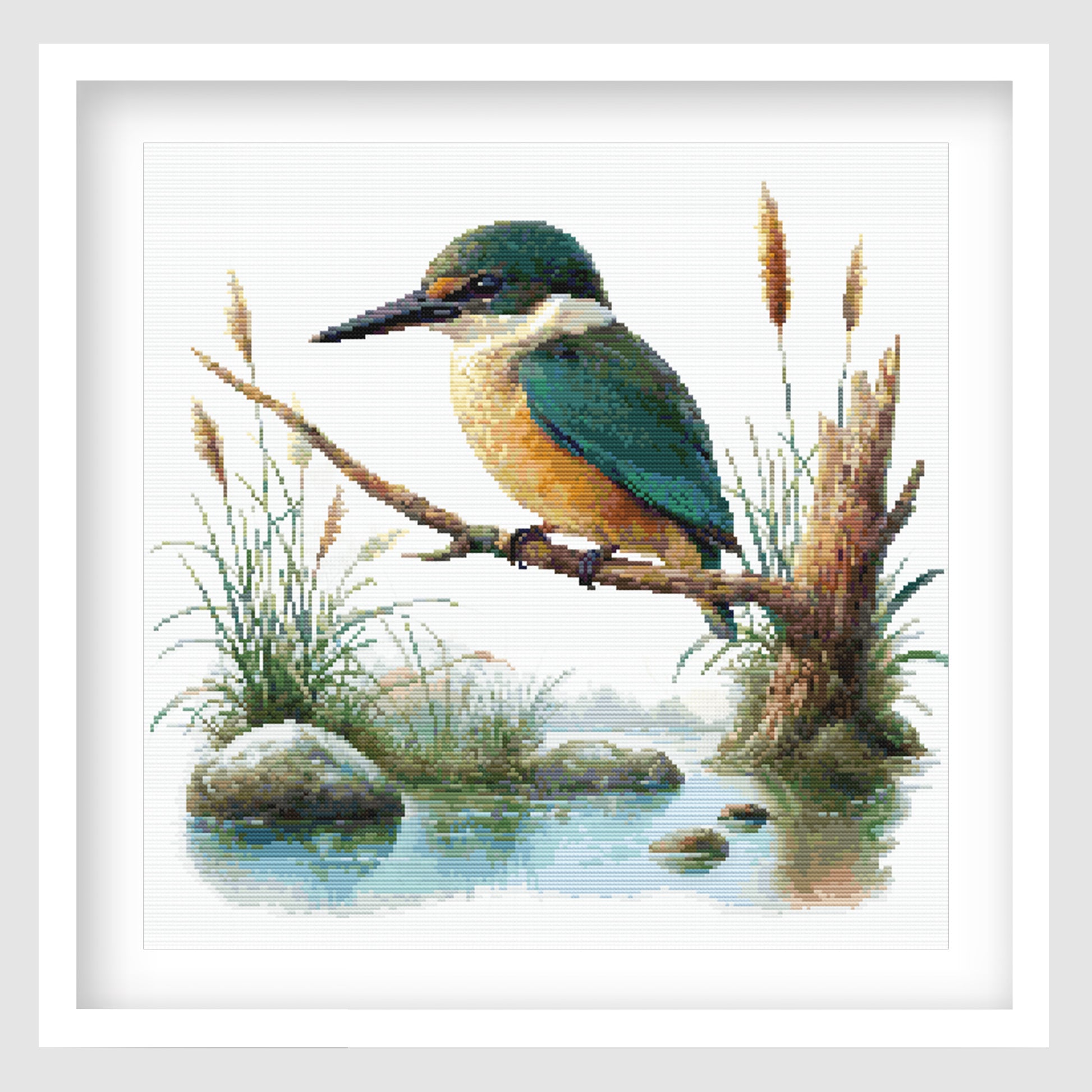 Sacred Kingfisher Kōtare Cross Stitch Pattern displayed as framed wall art with a native New Zealand kingfisher, blue-green feathers, reeds, water, and natural wetland detail.