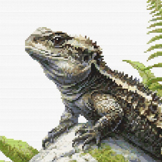 Close-up of Tuatara Cross Stitch Pattern showing the tuatara head, textured scales, fern detail, and visible counted cross stitch texture.