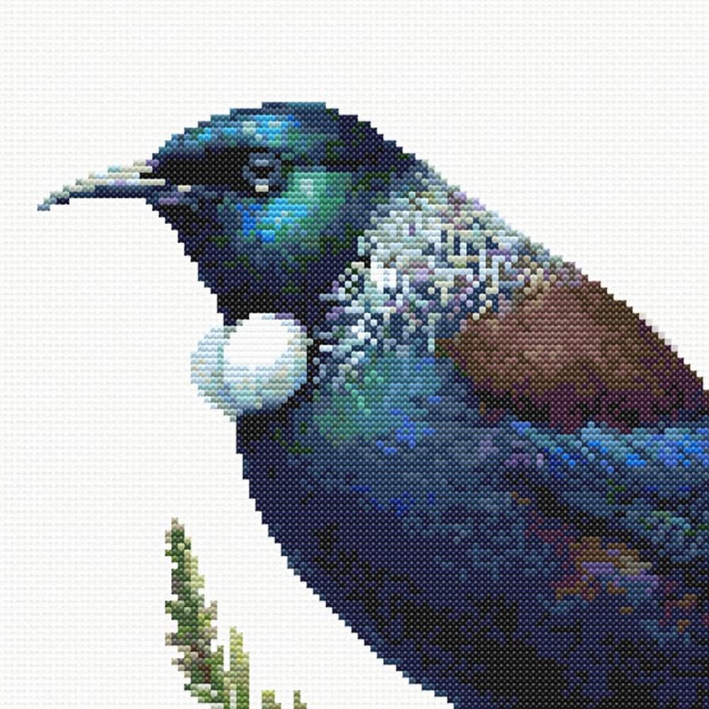 Close-up of Tui Cross Stitch Pattern showing glossy dark feathers, blue-green colour, white throat tuft, and visible counted cross stitch texture.