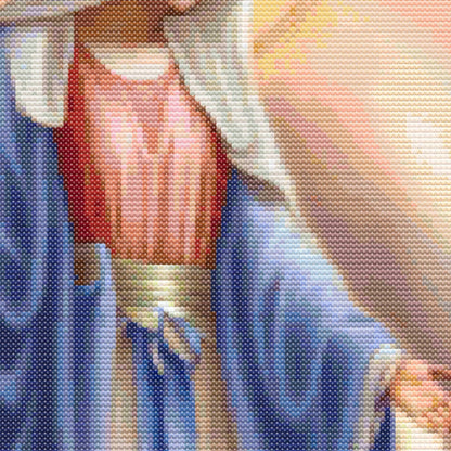 Close-up of Virgin Mary cross stitch pattern showing detailed robe stitching, soft colours, and religious embroidery texture.